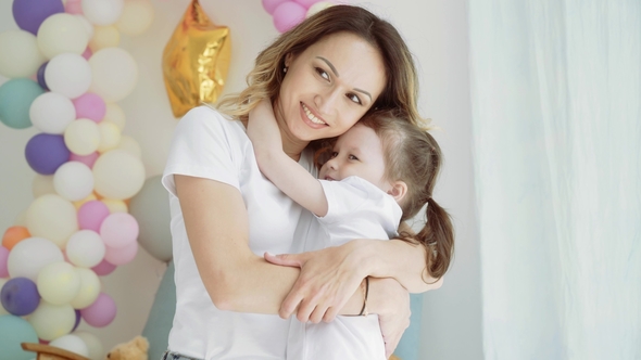 Little Girl Hugging with Mom. A Woman Kisses Her Little Daughter