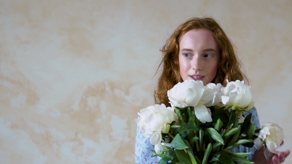 Portrait of Red Haired Girl Sniffs a Big Bush of White Peonies