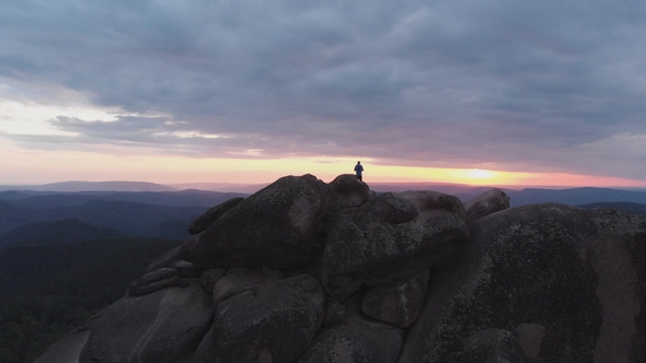 Aerial View of the Lonely Man Standing on Top of a Cliff and Enjoying the Sunset.