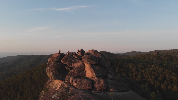 Aerial View of the Three Friends Sitting on Top of the Mountain and Watching the Sunset