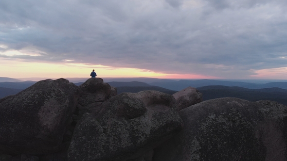 Aerial View of the Lonely Man Standing on Top of a Cliff and Enjoying the Sunset.