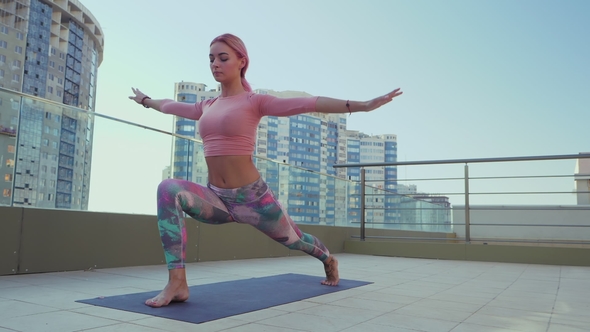 Young Slim Healthy Woman with Pink Dyed Hair Doing Yoga Practice and Pilates Exercises on Skyscraper alt