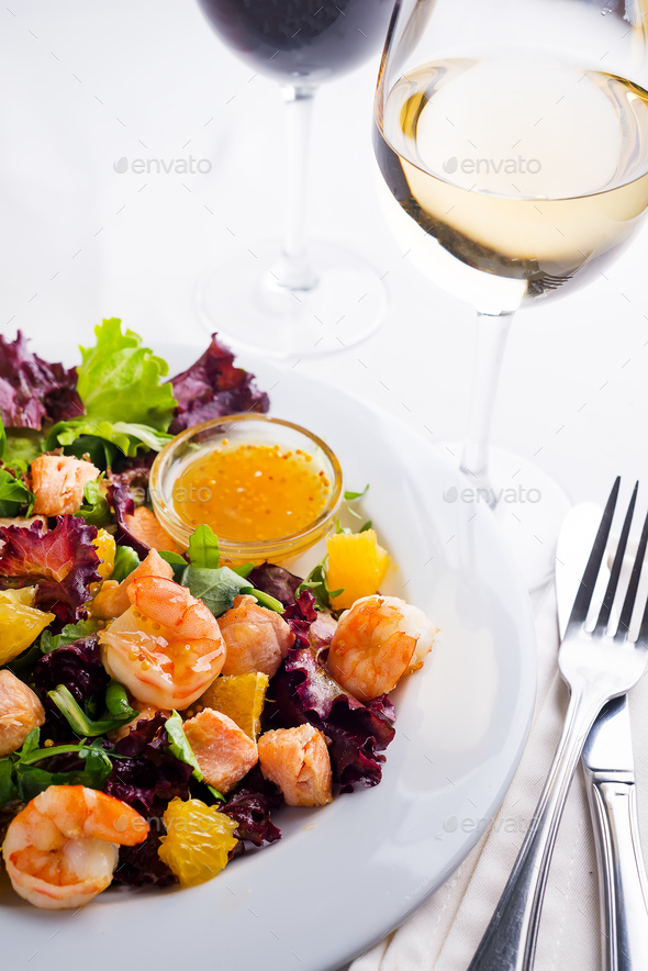 Healthy salad with prawns, lettuce, oranges and mango served on a plate with orange mustard sauce - Stock Photo - Images