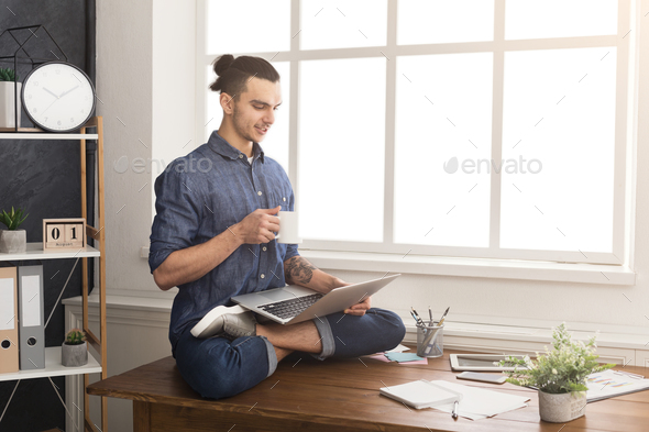 Flexible man practicing yoga at workplace Stock Photo by Prostock-studio