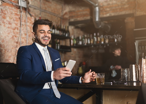Happy businessman resting in bar after working day Stock Photo by Prostock-studio
