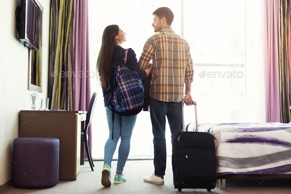 Young couple with luggage in hotel room Stock Photo by Prostock-studio