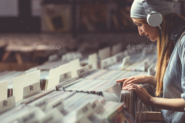 Young girl with headphones browsing vinyl records Stock Photo by AboutImages