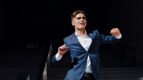 Happy Young Businessman in Black Suit Throws Out Documents Outdoor Against Office Building.  Vide