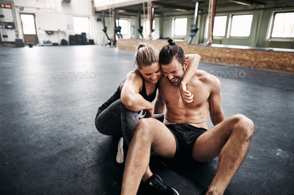 Affectionate young couple sitting in a gym after working out Stock Photo by UberImages