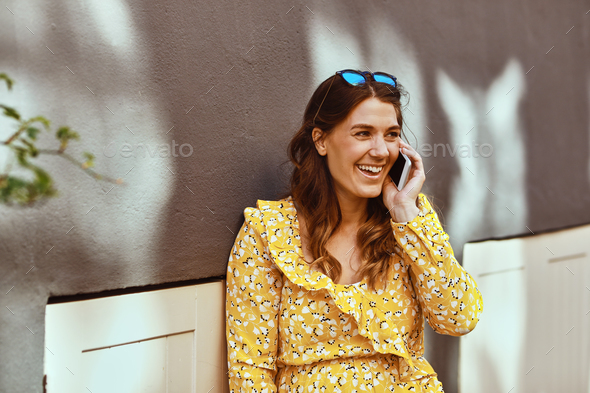Smiling woman sitting in the city talking on her cellphone Stock Photo by UberImages