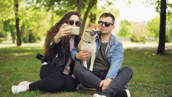 Pretty Woman Is Taking Selfie with Her Boyfriend and Adorable Dog Using Smartphone While Resting in alt