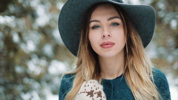 Portrait of Stylish Young Beautiful Woman in Green Coat and Hat Walks Around in the Winter Forest