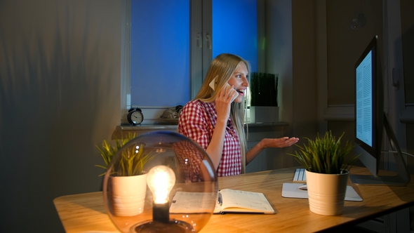 Happy Female at Computer Talking on Smartphone. Cheerful Amazed Blond ...