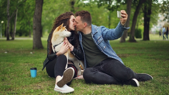 Handsome Young Man Is Taking Selfie with His Girlfriend Who Is Holding a Dog alt