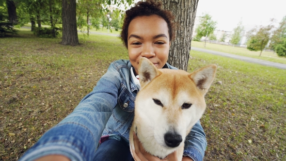Point of View Shot of Pretty African American Girl Taking Selfie with Cute Puppy in City Park alt
