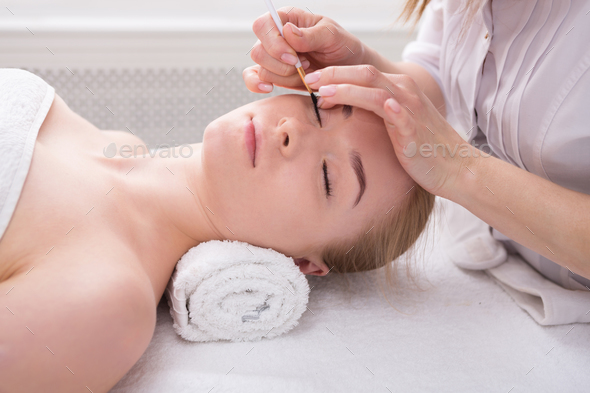 Woman gets eyelashes tinting by beautician at spa - Stock Photo - Images