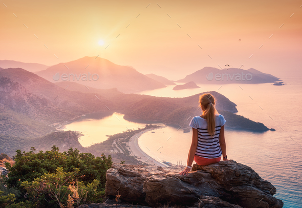 Young woman sitting on the top of rock and looking at the seasho - Stock Photo - Images