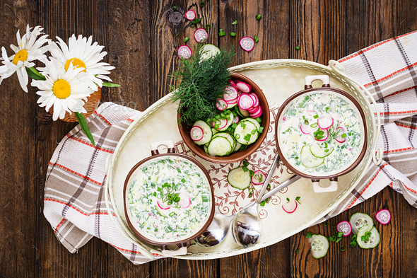 Cold soup with fresh cucumbers, radishes with yoghurt in bowl on wooden background. - Stock Photo - Images