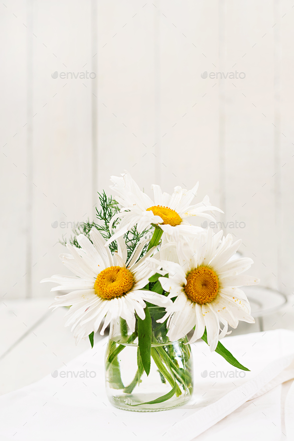 Bouquet of daisies in vase on a wooden white table Stock Photo by Timolina