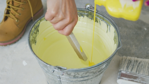 Hand Mixing Yellow Wall Paint in Bucket alt