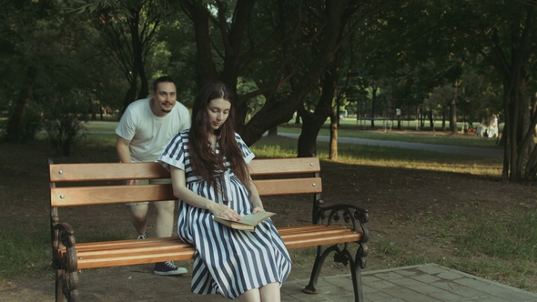 Affectionate Man Embracing His Pregnant Wife in Park alt