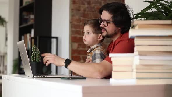 father with a son at working place in home office alt