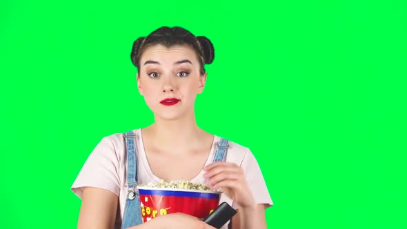 Woman Chews Popcorn and Changing Channels with TV Remote. Green Screen, Slow Motion alt