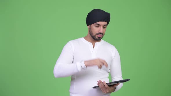 Young Stressed Bearded Indian Man Using Digital Tablet and Getting Bad News