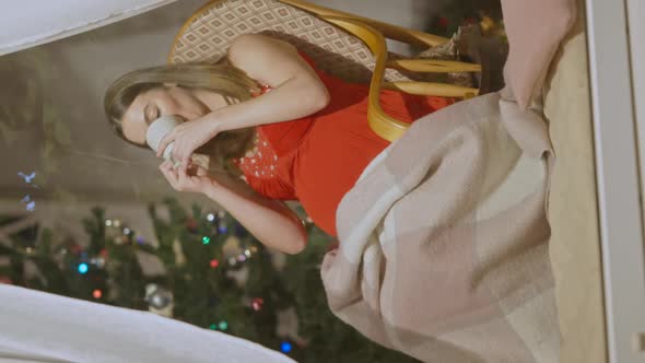 Vertical Video Happy Pregnant Woman in Red Dress Sitting on Rocking Chair Drinking Hot Tea and alt