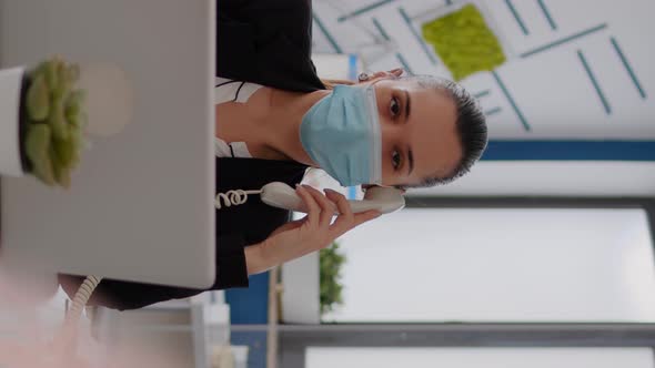 Vertical Video Entrepreneur with Protective Face Mask Discussing on Landline alt