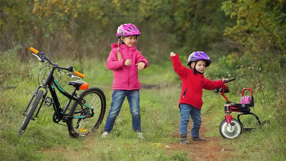 Little boy and girl, brother and sister, dancing near bicycles outdoors. autumn comes.