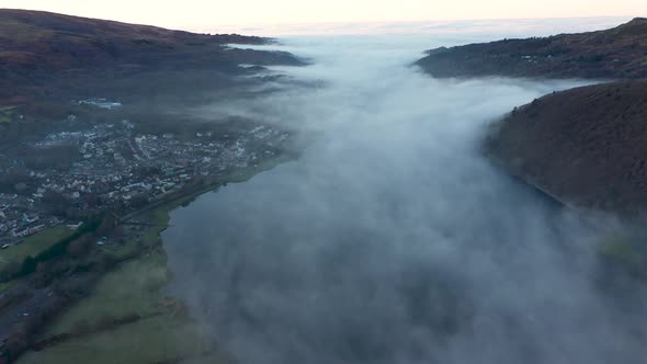 Aerial view of a lake and town covered by fog and clouds at sunset