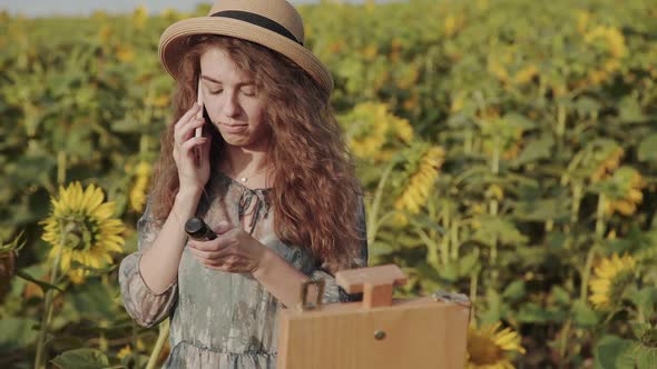 Happy Lady Speaking on the Mobile Phone Among Beautiful Summer Sunflowers alt