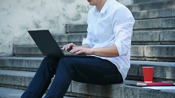 Student Sitting On Stairs And Typing On Laptop.