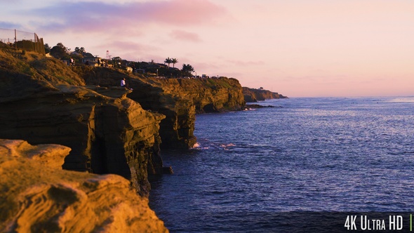 4K Woman Sitting on Rocky Sunset Cliffs Coastline in San Diego, California alt