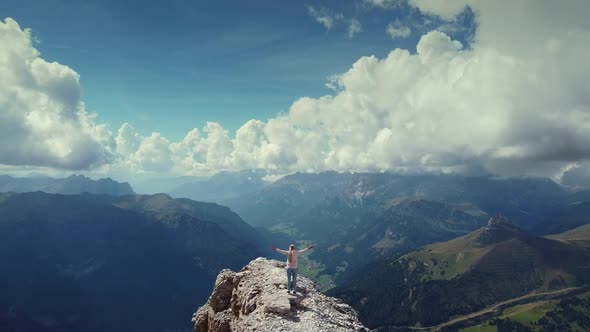 Flying Over Woman with Raised Hands Standing on Piz Boe Mountain Top in Dolomites alt