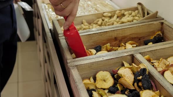 Closeup of a Salesman Pouring Dried Fruit Into a Box in a Grocery Store alt
