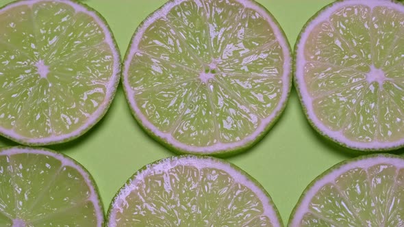 Fresh Green Limes Cut Into Pieces on a Green Background
