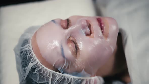 Mask for the face. Beautiful woman in spa salon, beautician applying face mask.