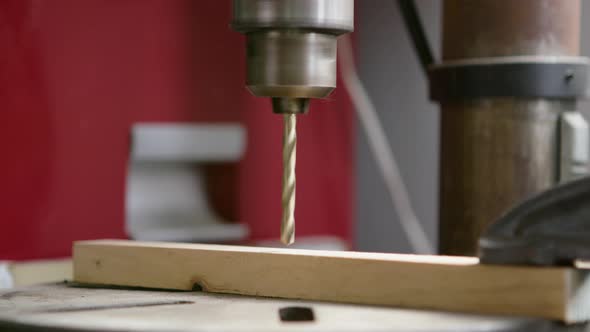 UHD close up of a drill press slowly drilling through a small piece of wood alt