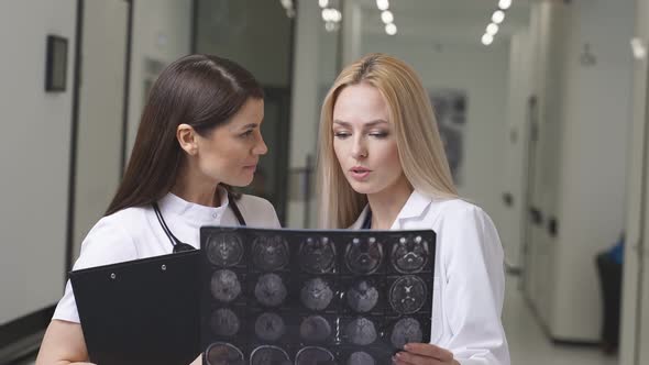 Two Young Doctors Looking At Computed Tomography Xray Image Discussing
