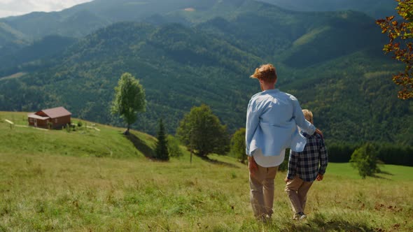 Father Hugging Son Walking on Mountain Hill alt