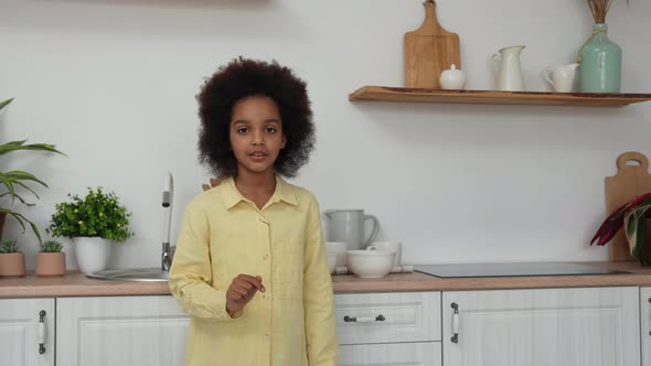 Little African American Girl Sets Deep White Bowls on the Table alt