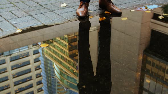 Reflection of a businessman in the puddle using digital tablet alt