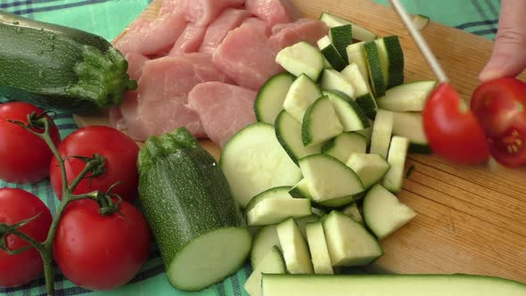 Fresh pork on the chopping board is cut into pieces with vegetables