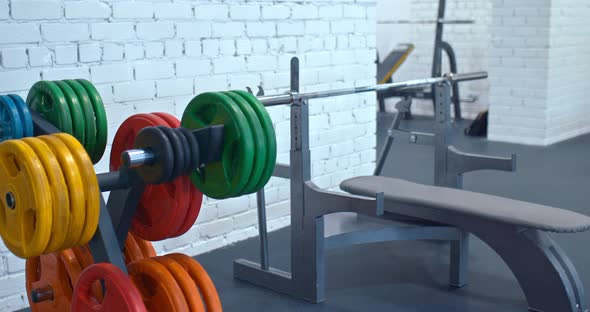 Barbell with Metal Pancakes Lies on a Counter in a Modern Gym alt