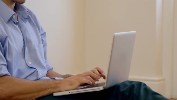 Man sitting on floor and using laptop alt
