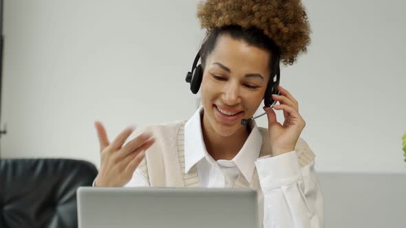 A Smiling AfricanAmerican Call Center Agent Wearing Headphones with a Microphone Talking to a Client alt