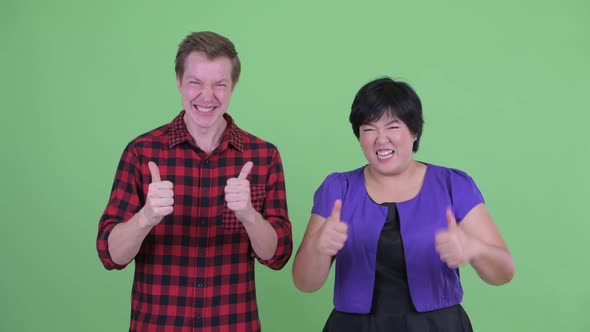 Happy Young Multi Ethnic Couple Giving Thumbs Up Together alt