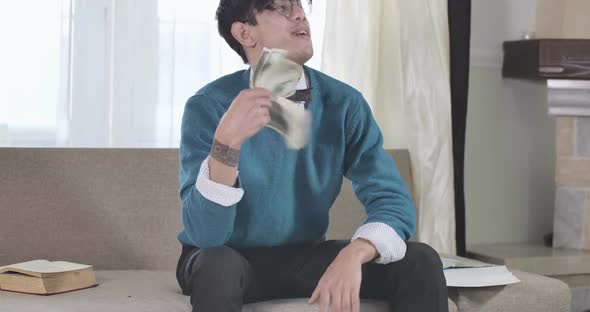 Rich Caucasian Guy in Eyeglasses Counting and Scattering Money As Sitting on Couch. Wealthy Young alt